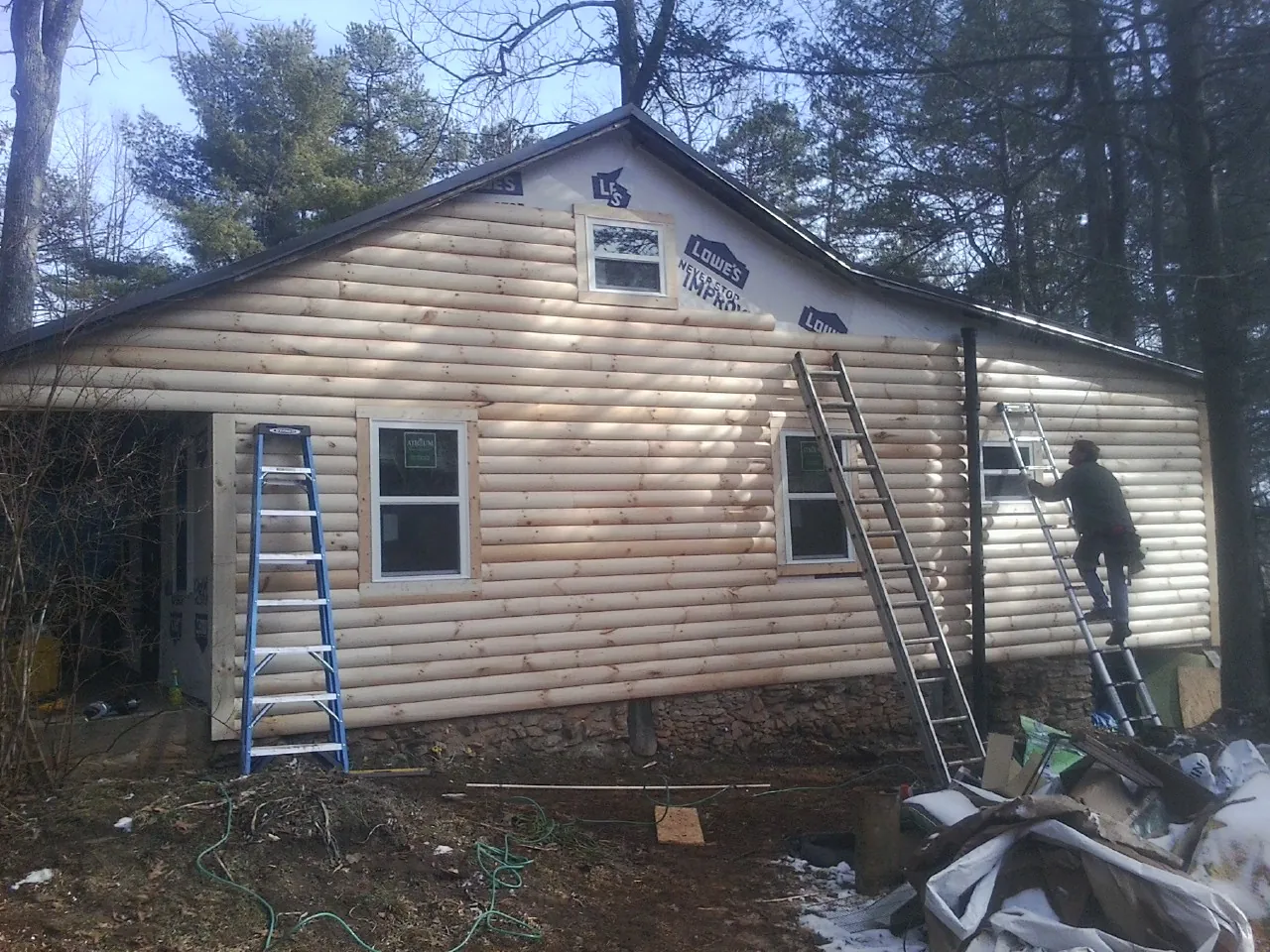 Ladders set against fresh log siding during an exterior remodel in Salem